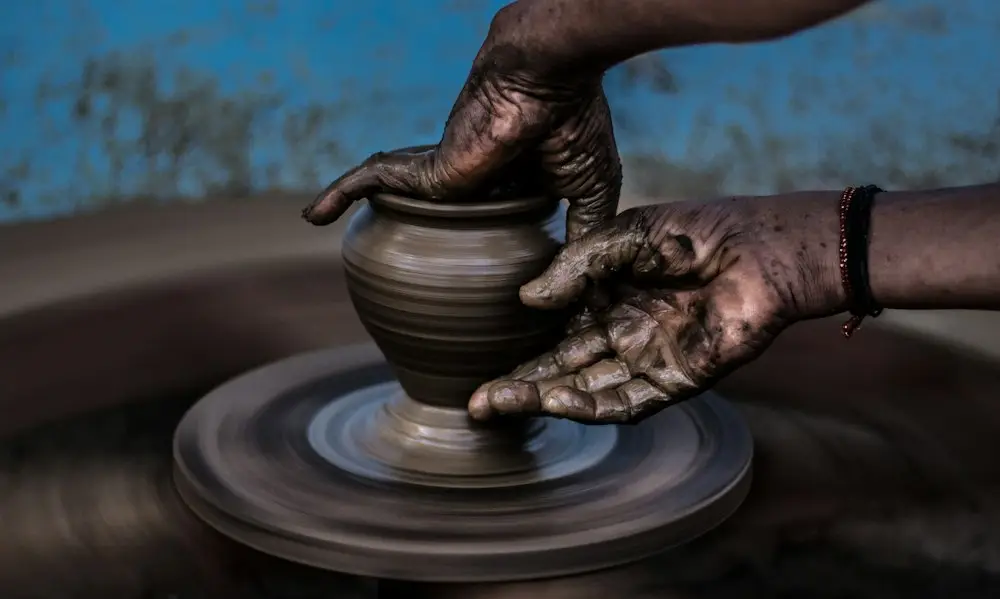 Hands shaping a pot on a potter's wheel